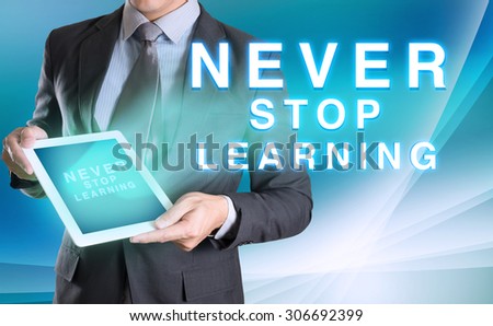 businessman holding tablet with NEVER STOP LEARNING word with abstract background for Business