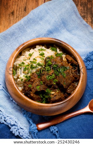 Slow cooked spicy beef curry with rice in a wooden bowl