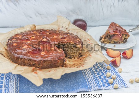 Plum, hazelnuts and chocolate home baked cake glazed with fruit jelly