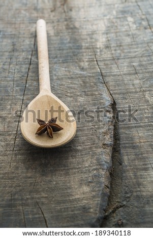 Wooden serving spoon with star anise, on old rustic wooden board