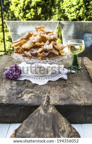 Frappe - typical Italian carnival fritters dusted with icing sugar, with a glass of desert wine in the background
