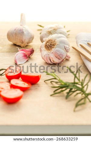 Fresh tomatoes, garlic and rosemary on wood table.   Cooking photo for recipe book or advertisement. healthy life.