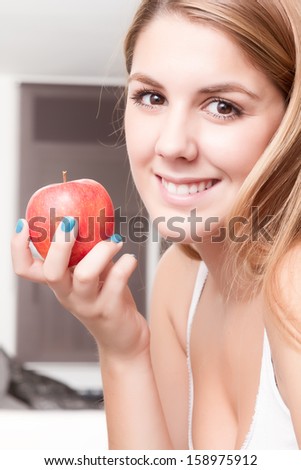 Young girl happy relaxed with an apple in her home