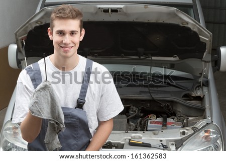 Portrait of happy mechanic repairing under car hood
