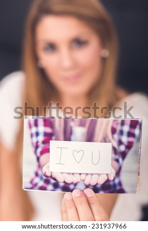 woman showing a picture of him where is a paper in hands with I love you