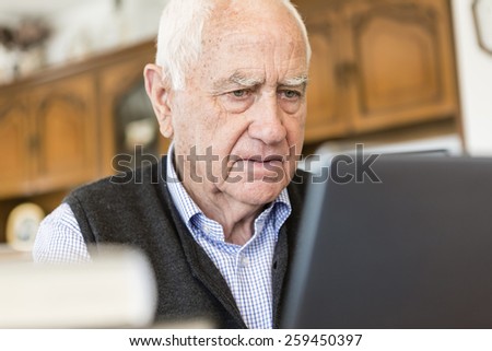 Senior man looking for information in books and internet