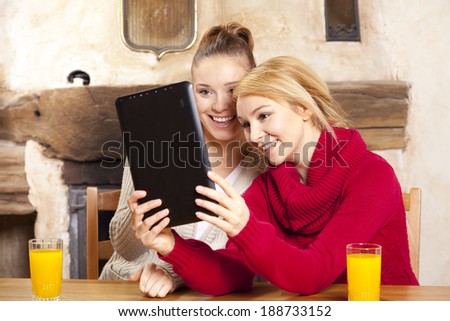 Two beautiful women work on the tablet during the holidays
