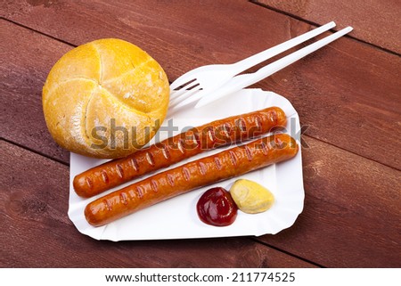 Roasted sausage with bread served on a paper tray - wood board