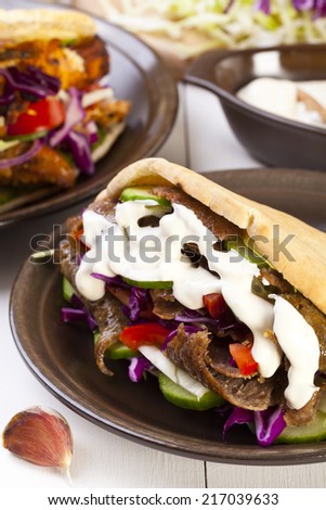 Beef Kebab in a bun with garlic sauce on woodboard