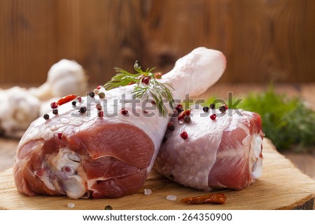 Raw turkey thigh with spices on a wooden board