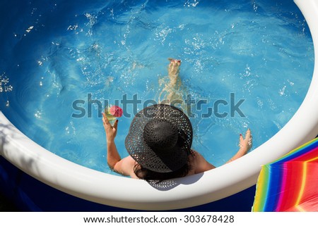 Young woman in a straw hat relaxing in the garden pool.