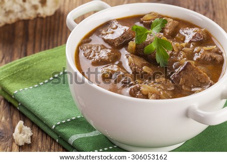 Beef stew served with bread in a plate on a wooden background
