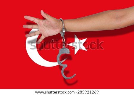 handcuffs with hand on Turkey flag