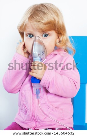 Baby girl with asthma problems making inhalation with mask on her face