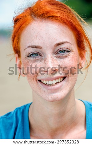 Portrait of a happy smiling beautiful young redhead woman with blue eyes and freckles