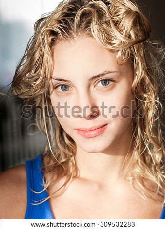 Closeup portrait of a beautiful blonde young smiling woman with no makeup, clear skin and blue eyes