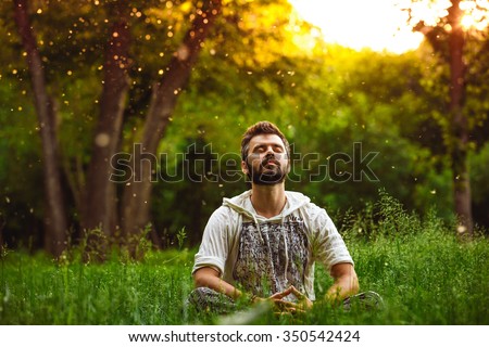 A bearded man is meditating on green grass in the park with face raised up to sky and eyes closed on sunny summer day. Concept of meditation, dreaming, wellbeing and healthy lifestyle Stockfoto © 