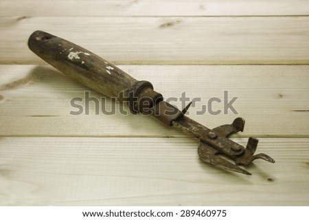 Old dirty, rusty can opener with wood handle