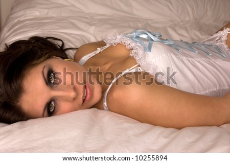 sexy and beautiful young woman on her back showing sexy eyes looking at the viewer in a white corset