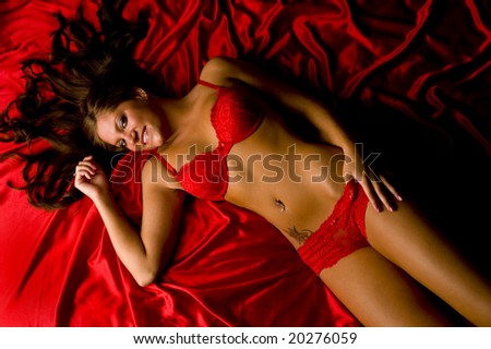 Sexy brunette on red satin sheet in red lingerie