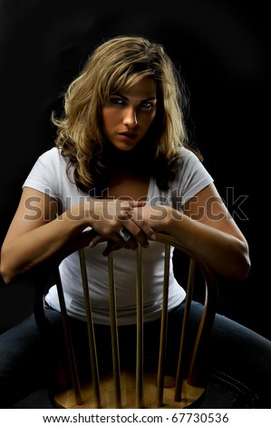 gorgeous blond woman straddling chair with dramatic lighting