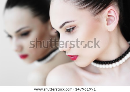 Haute couture look.glamour a portrait of fashion of beautiful sexual female model of the woman of the brunette with bright cosmetics and red lips and its reflection in mirrors on a light background