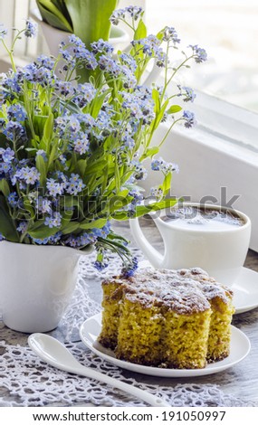 Polenta cake with cup of Coffee. Near forget me nots on rustic wooden table.