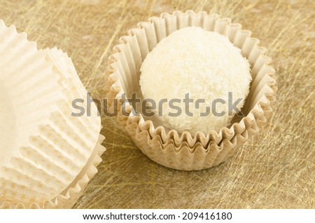 White, round, coconut chocolate sweats and paper packaging on golden background From series elegant desserts