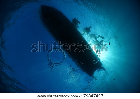 Silhouette of a dive boat and divers on the surface of the water with a bubble ring - Akumal, Riviera Maya, Mexico