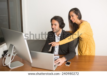 Business couple working at the computer looking at the camera th