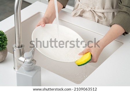 Close up of woman housewife is doing the dishes at home kitchen by using wash sponge and dishwashing. Stock foto © 