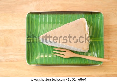 Crepe cake on banana leaf plate and wooden fork, on the wooden table.