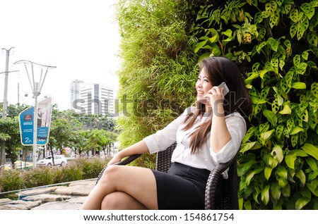 Pretty young business woman using mobile phone outdoor, tree background.