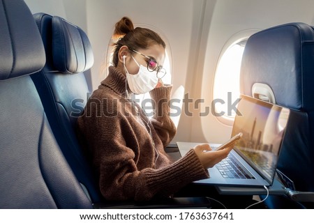 A young woman wearing face mask is traveling on airplane , New normal travel after covid-19 pandemic concept 