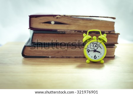 Vintage of green alarm clock and stack of books on a white background,selective focus