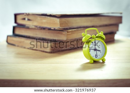 Vintage of green alarm clock and stack of books on a white background,selective focus
