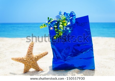 Starfish with blue gift bag on sandy beach in sunny day- holiday concept