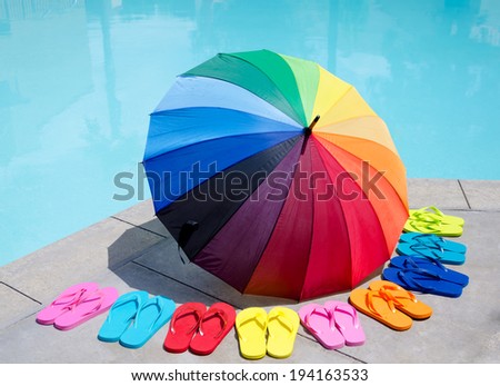 Color umbrella and flip flops by the swimming pool in sunny day