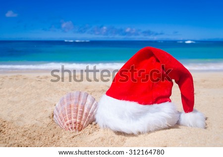 Merry Christmas and Happy New Year background with Santa Claus Hat and seashell on the tropical beach near ocean in Hawaii