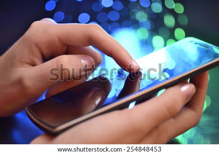 Hand Touching Smart Phone On Blurry Blue And Green Background
