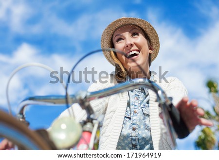 young woman happy bicycling at park behind a blue sky