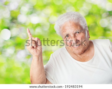 portrait of adorable old woman pointing up with her finger