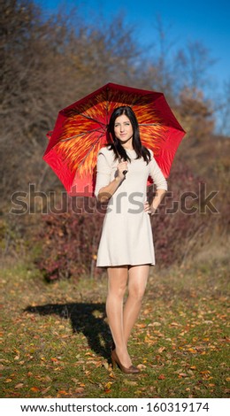 Beautiful brunette young woman with red umbrella outdoors