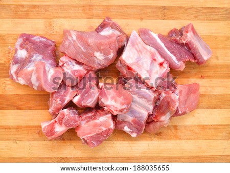 Slices of fresh raw pork meat isolated in wooden board on white background