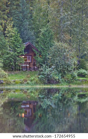 Cabin in the woods on the edge of a lake.