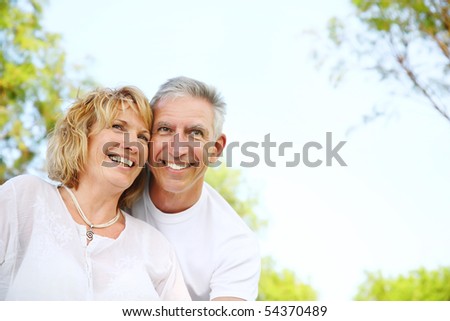Lifestyle portrait of a mature couple smiling and embracing in the nature. Focus on the woman.