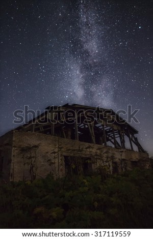 The Milky Way over an old shed. The Milky Way over ruins. Starlit night. Milky Way
