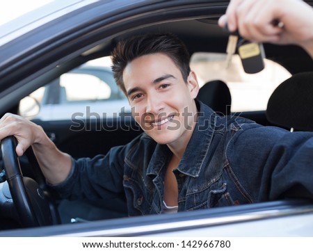 Happy young man holding keys to new car