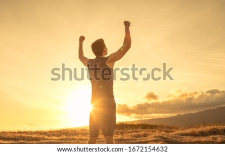 Strong fit young man raising fist up the sunset sky. People victory and triumph.  商業照片 © 