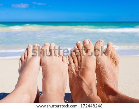 Vacation holiday. Close up of young couple feet relaxing on beach.